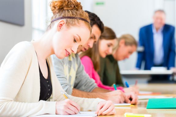 Studenten beim Lernen in der Klasse, im Hintergrund der Dozent